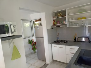 Una cucina moderna con mobili bianchi, piano cottura a gas, forno integrato e un tostapane in acciaio inossidabile.