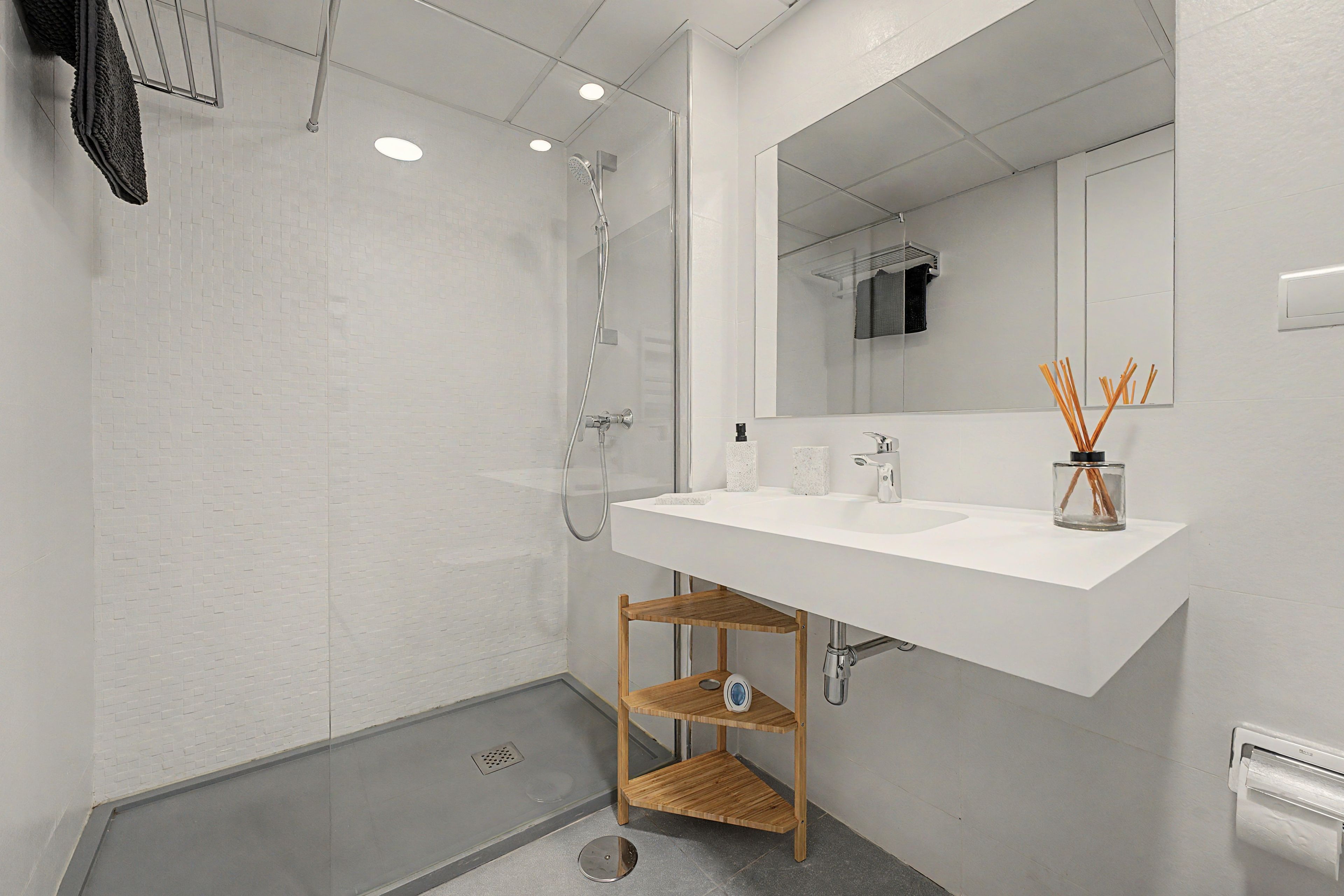 A modern bathroom with a white sink, mirror, and shower.