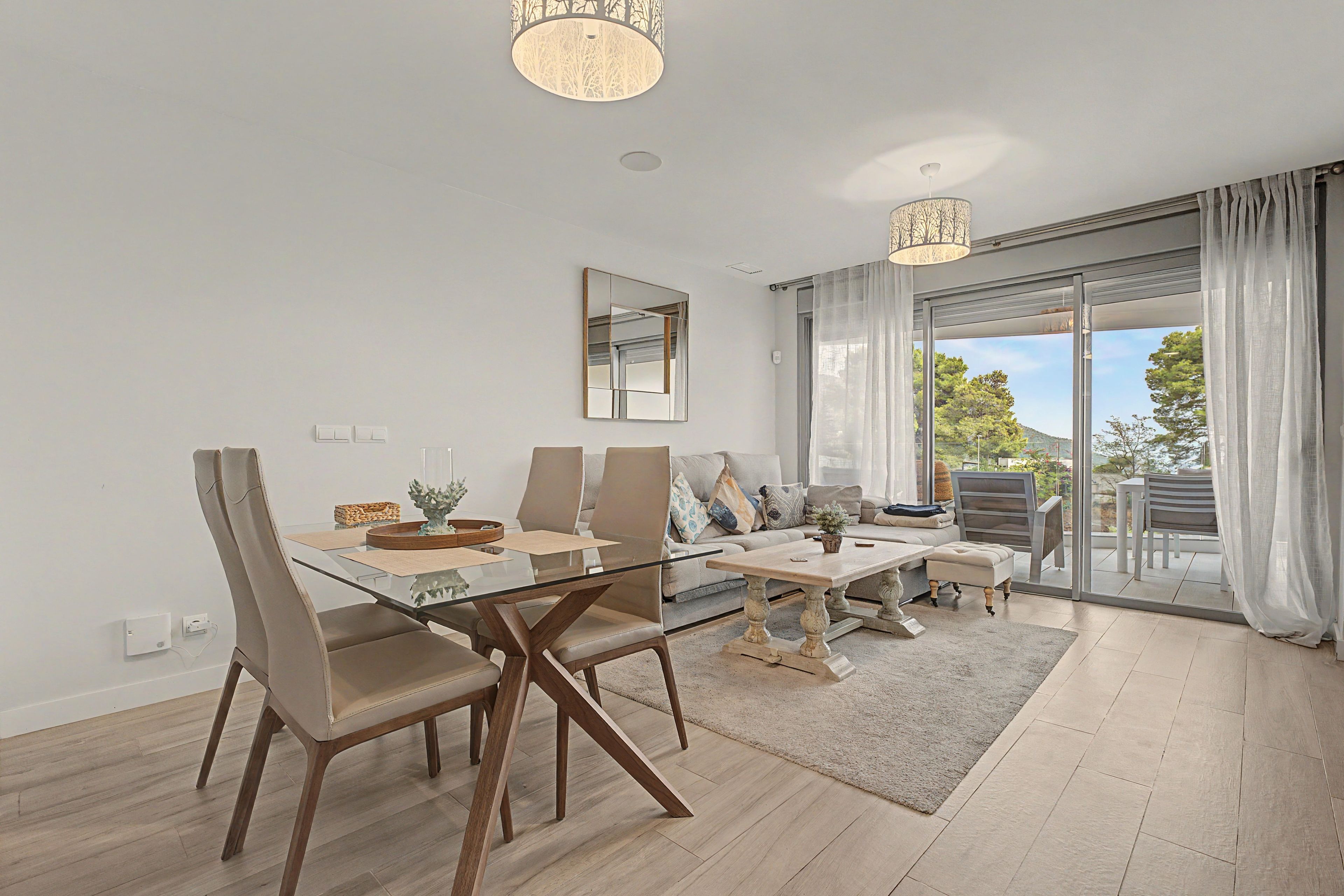 A modern living room with a glass dining table, leather chairs, a sofa, and a coffee table.