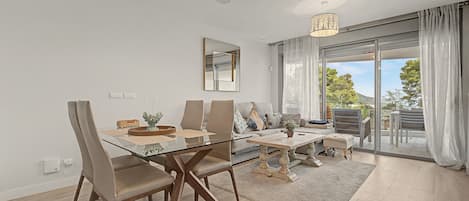 A modern living room with a glass dining table, leather chairs, a sofa, and a coffee table.