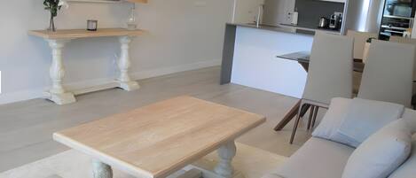 Una sala moderna con una mesa de centro de madera, un sofá y un comedor con mesa y sillas.
