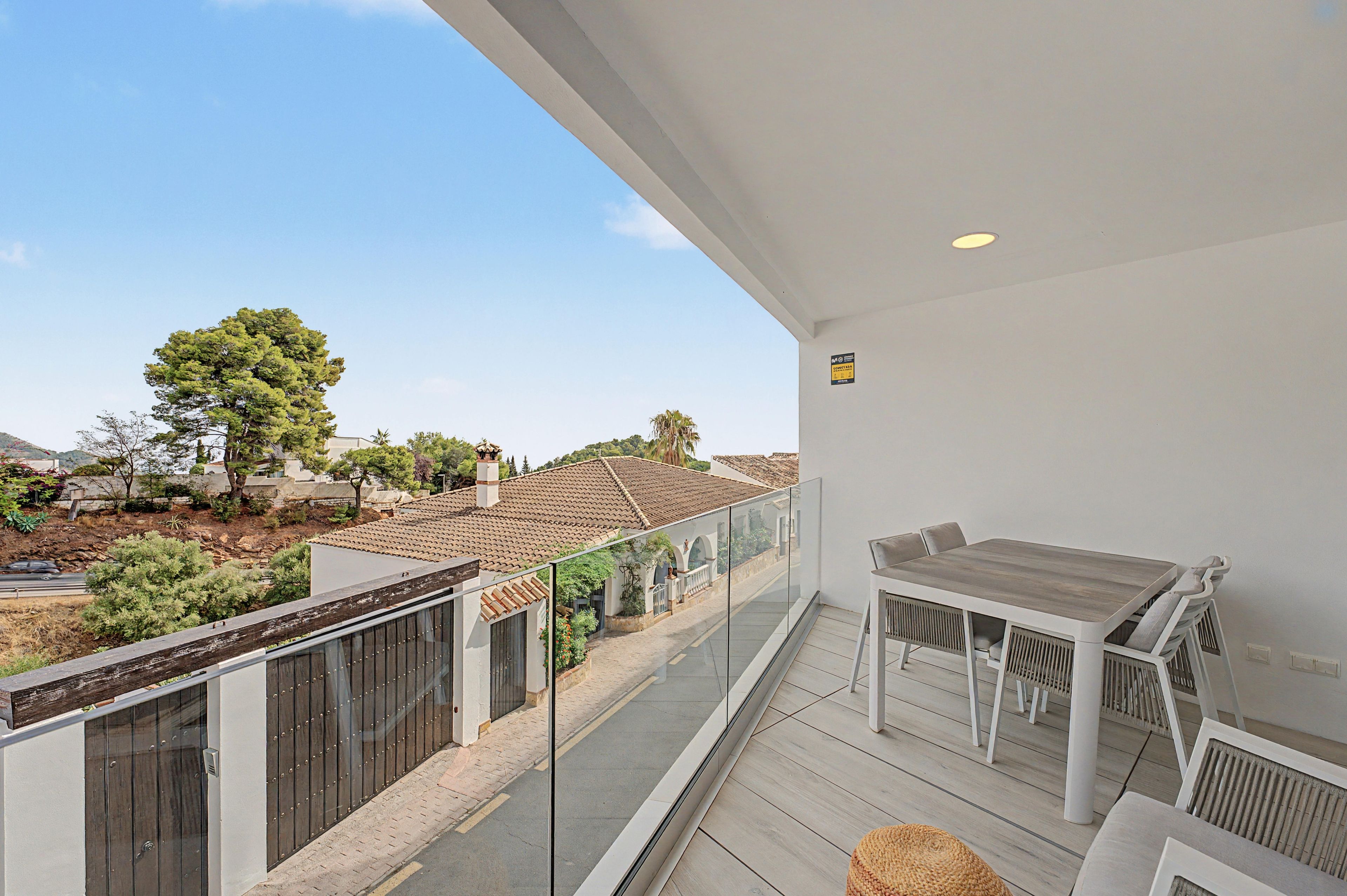 A balcony with a view of a residential area, a table, and chairs.