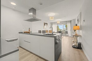 Een moderne keuken met een centraal eiland, roestvrijstalen apparatuur en uitzicht op het buitenleven.