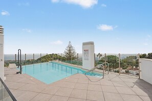 Una piscina en la azotea con vistas despejadas del paisaje circundante, incluyendo árboles y edificios a lo lejos.