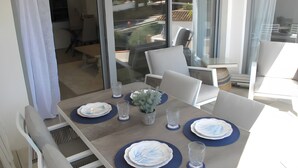 A dining area with a table set for four, chairs, and a view through a glass door. - ‘In Inbisa’ Apartment with Sea Views, Wi-Fi & Air Conditioning (Mijas)