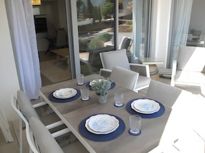 Comedor con mesa dispuesta para cuatro personas, sillas y vistas a través de un ventanal.