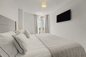 Habitación de hotel moderna con una cama grande, un televisor de pantalla plana y vistas al exterior.