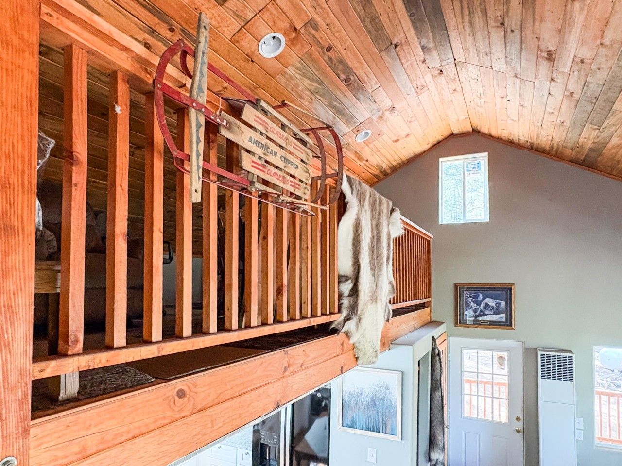 Ein Holzhäuschen-Interieur mit Schlafkoje, Holzbalken und aufgehängtem Tierfell.