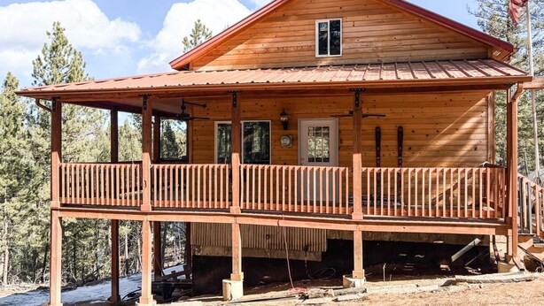 A wooden cabin with a balcony, a door, and an American flag. - Ricks Mountain Retreat (Sedalia)