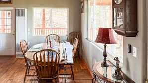 A dining area with a wooden ceiling, a ceiling fan, a dining table with chairs, and a clock on the wall. - Ricks Mountain Retreat (Sedalia)