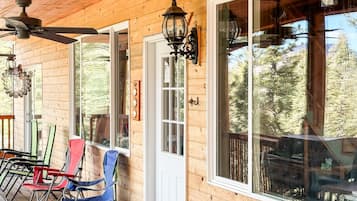 Une cabane en bois avec une véranda, un ventilateur de plafond et une rangée de chaises pliantes.
