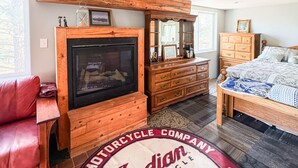 A room with a fireplace, wooden furniture, a bed, and a red leather couch. - Ricks Mountain Retreat (Sedalia)