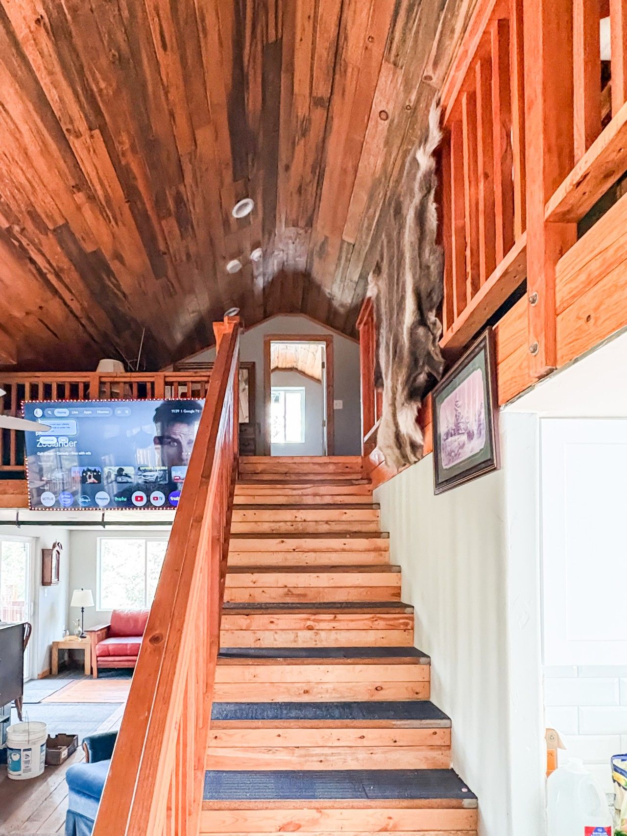 Un escalier en bois, doté d’une rampe, mène à un espace situé au deuxième étage.