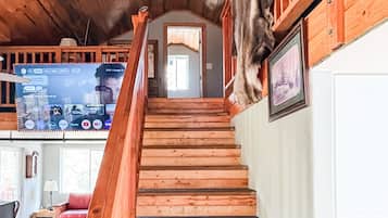 Un escalier en bois, doté d’une rampe, mène à un espace situé au deuxième étage.