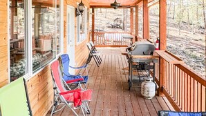 A covered outdoor deck with wooden flooring, ceiling fans, and seating arrangements. - Ricks Mountain Retreat (Sedalia)