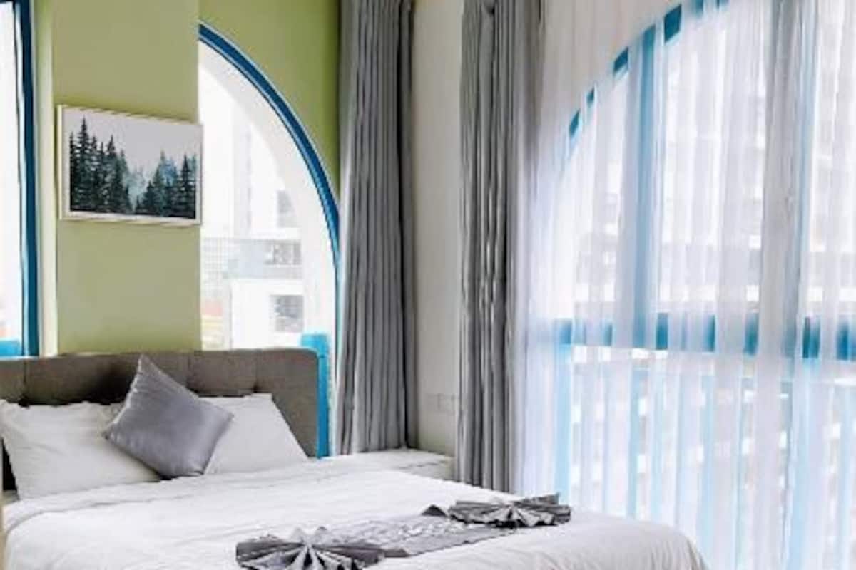 Quarto de hotel com cama, janela com cortinas e vista para o exterior.