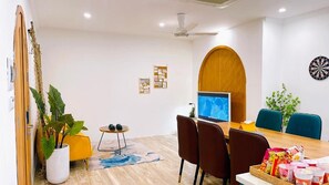 Uma sala de estar moderna com televisão, assentos, uma mesa de centro e um alvo de dardos.