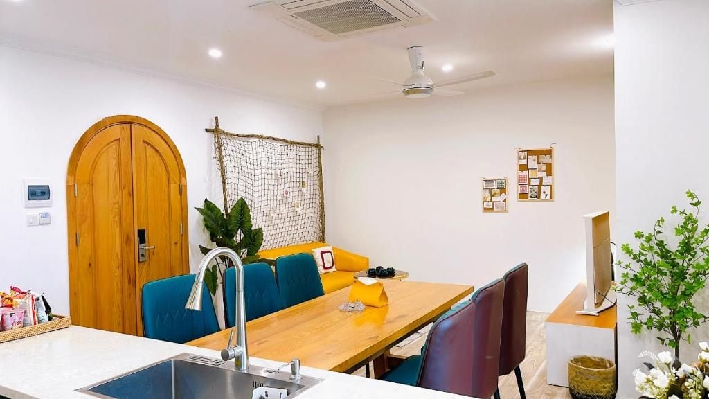 Una cocina moderna con un lavamanos, armarios de madera y una zona de comedor con mesa y sillas.