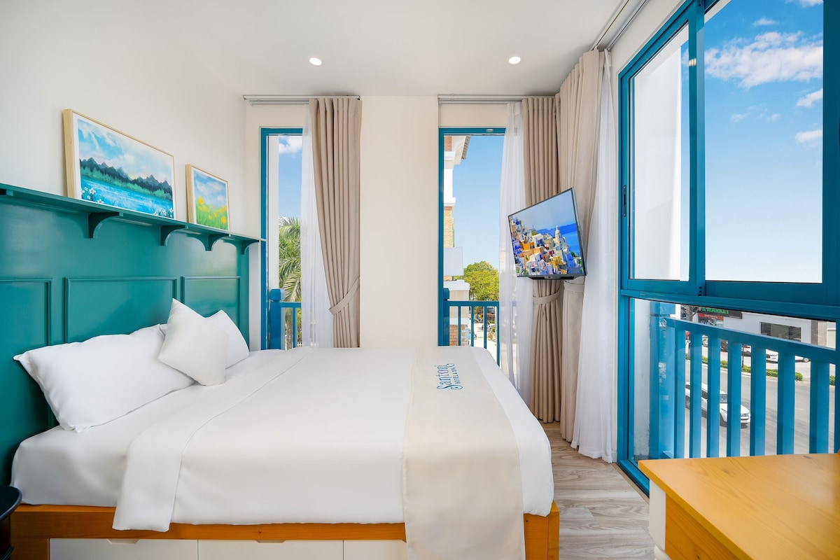Quarto de hotel com cama, televisão e varanda com vista.
