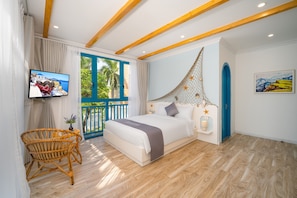 Quarto com cama, televisão, cadeira de vime e vista para o verde pela janela.