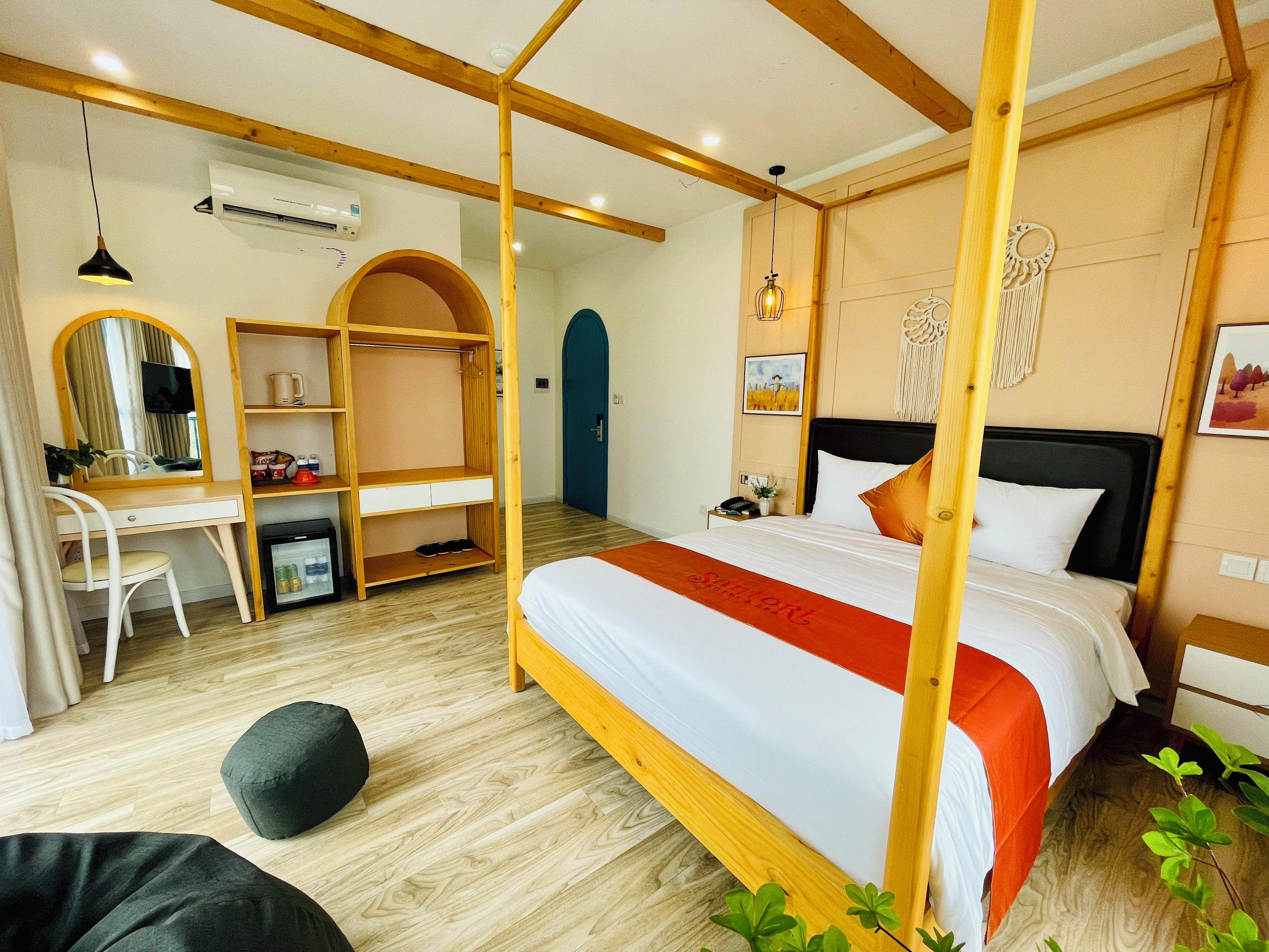A bedroom with a bed, a desk, a wardrobe, a mirror, and a door.