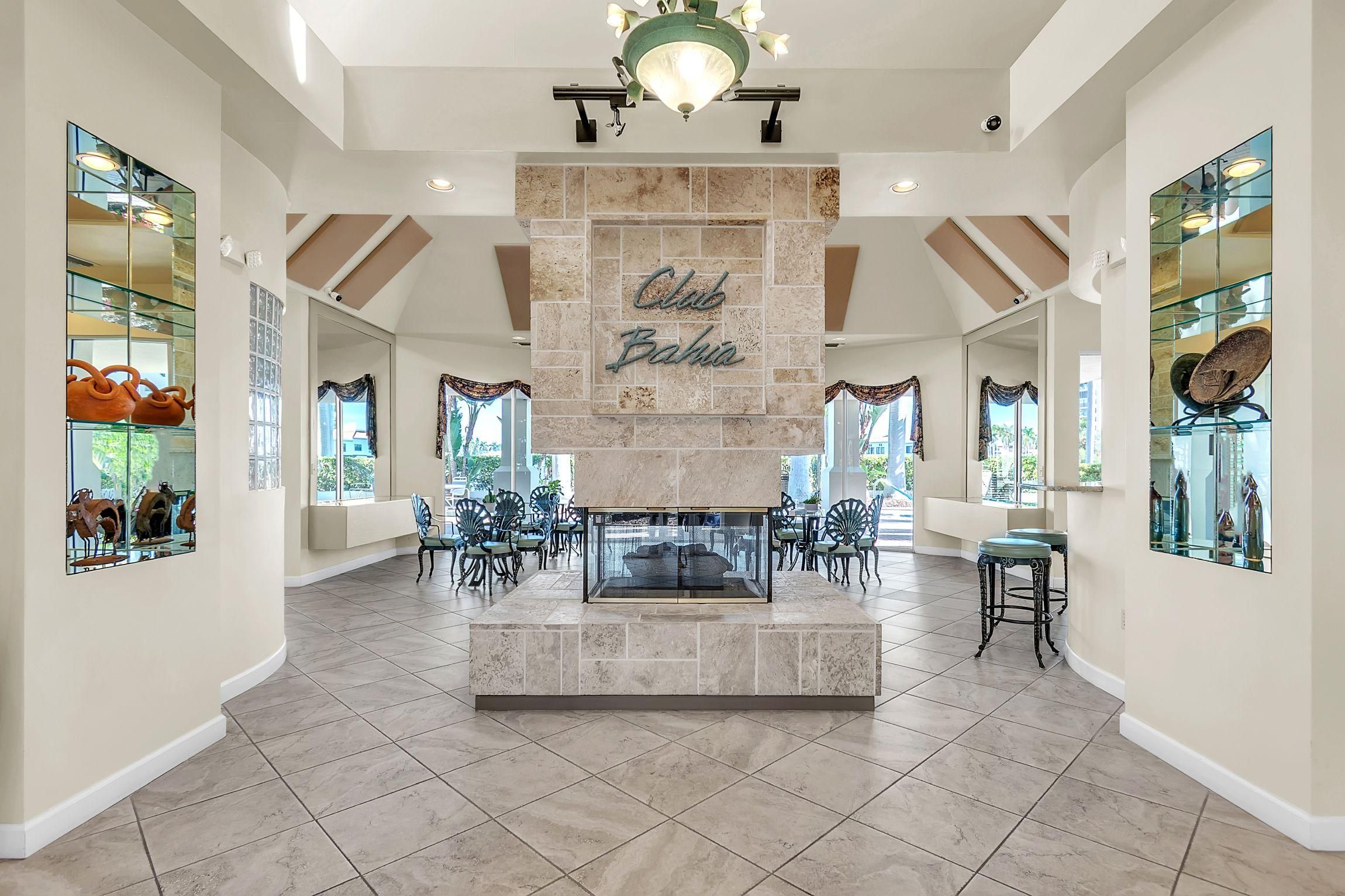 A spacious lobby with a central stone fireplace, glass display cases, and a chandelier.