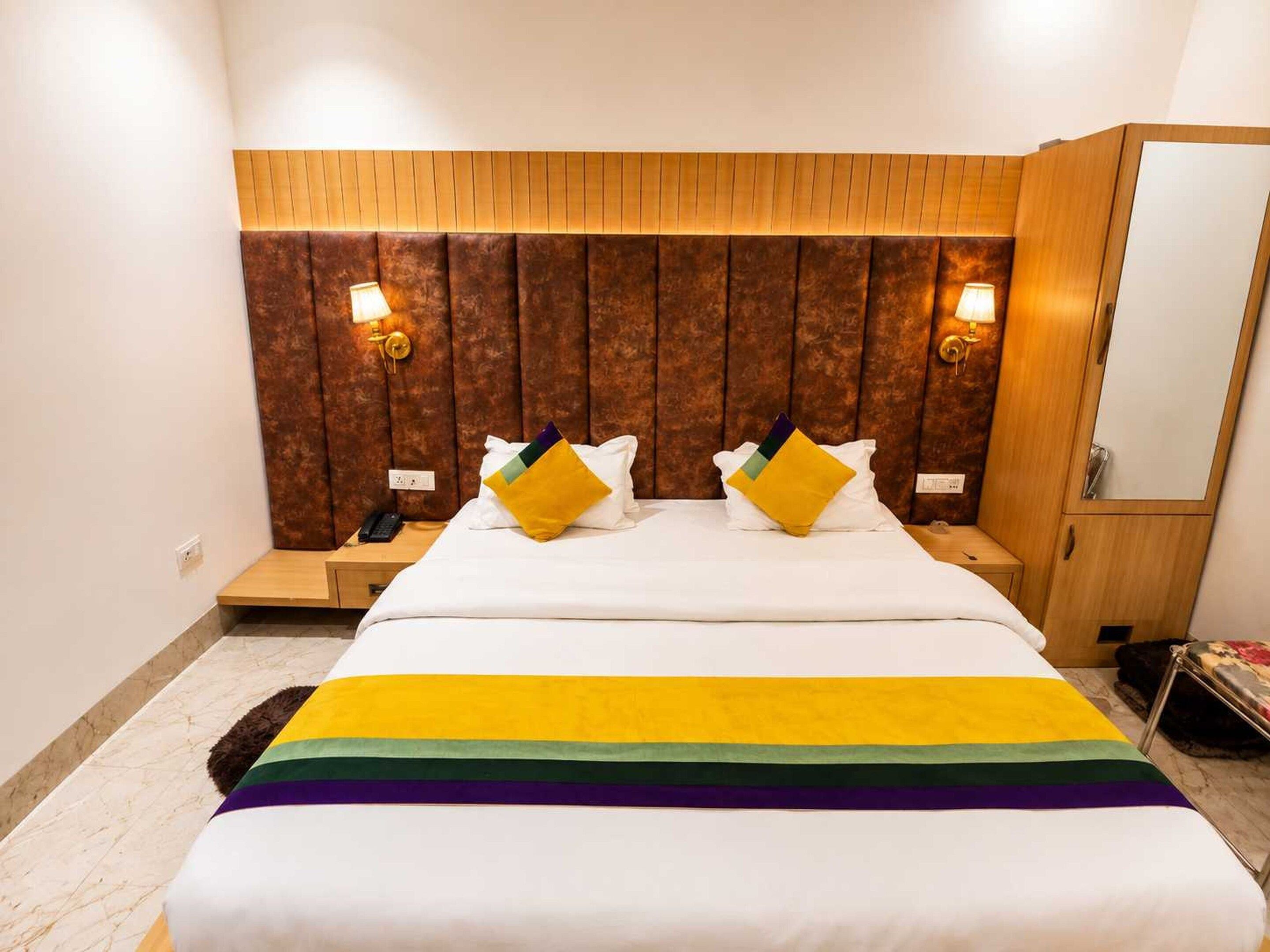 A hotel room with a large bed, two bedside tables, a wooden headboard, and wall-mounted lamps.