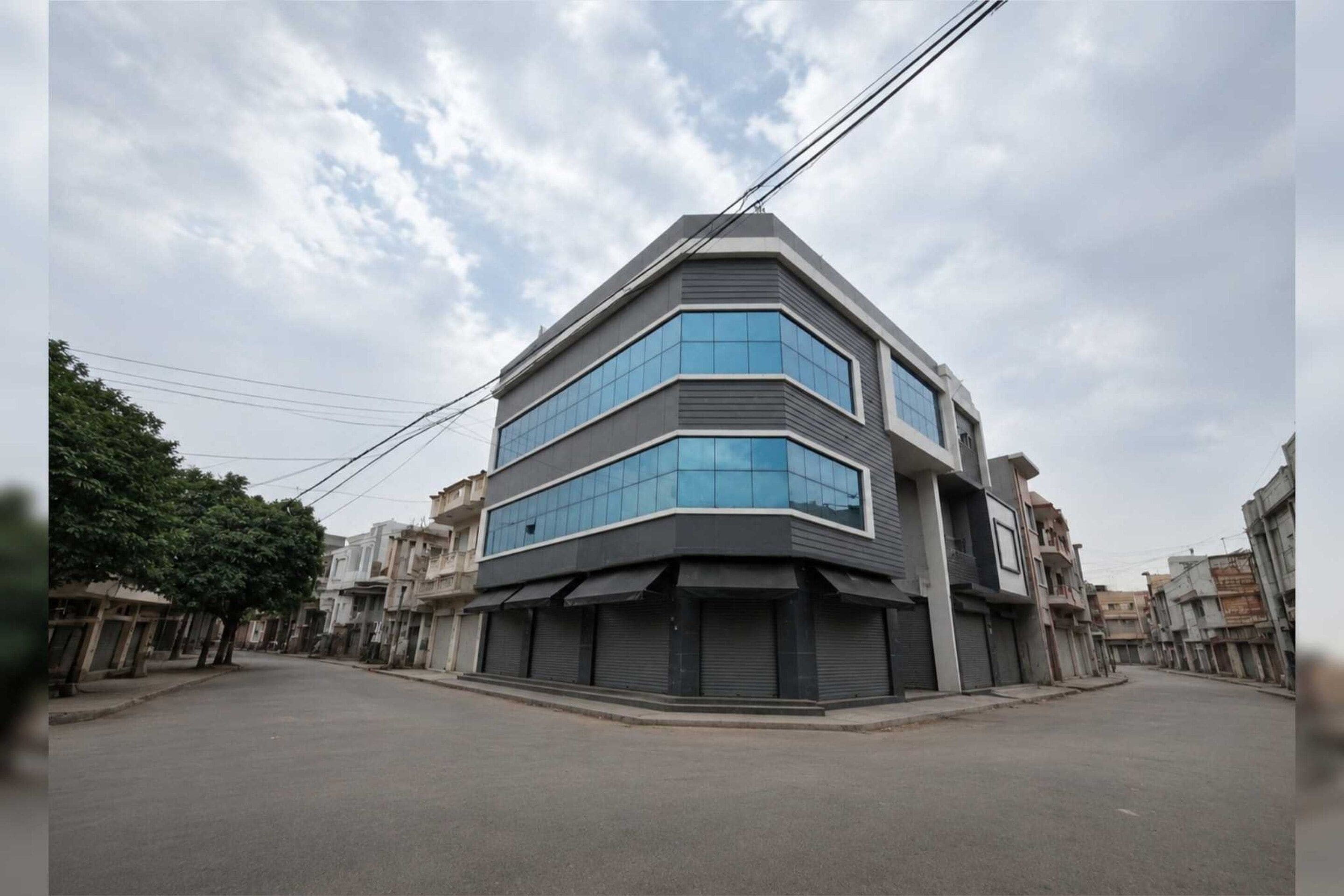 A modern building with a corner design, featuring large windows and a flat roof.