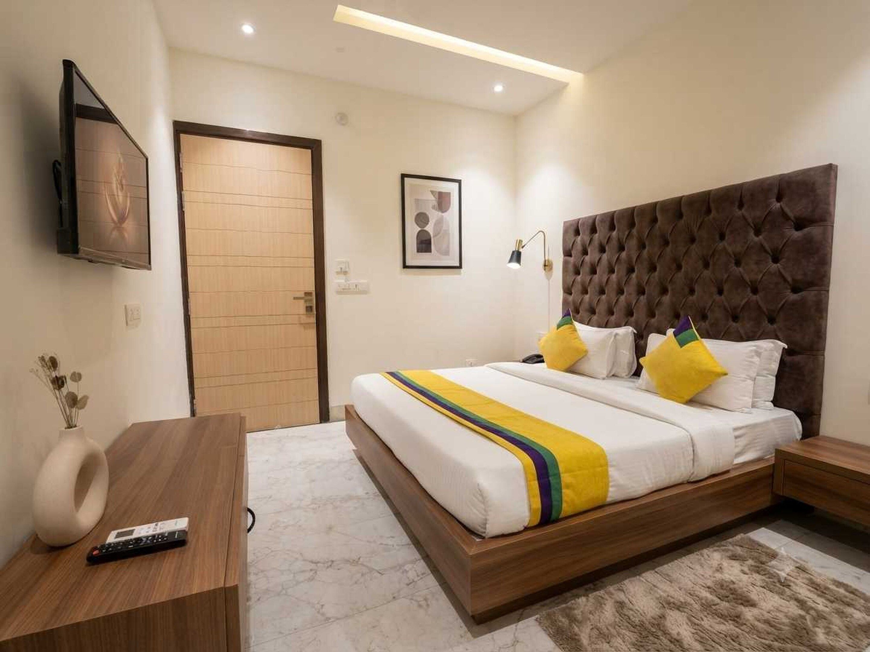 A modern bedroom with a wooden bed frame, a tufted headboard, and a bedside table with a remote control.