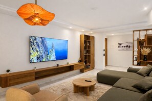 A modern living room with a large flat-screen TV, a wooden entertainment unit, a sofa, and a coffee table. - Modern & Luxury Apartment - (Izdihar) Marrakech (Marrakech)