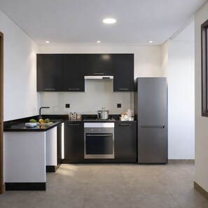 A modern kitchen with black cabinets, a stainless steel refrigerator, and a built-in oven. - Modern & Luxury Apartment - (Izdihar) Marrakech (Marrakech)