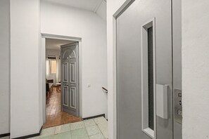 Ein Flur mit einer Tür zu einem Zimmer mit einem Bett und einem Fenster.