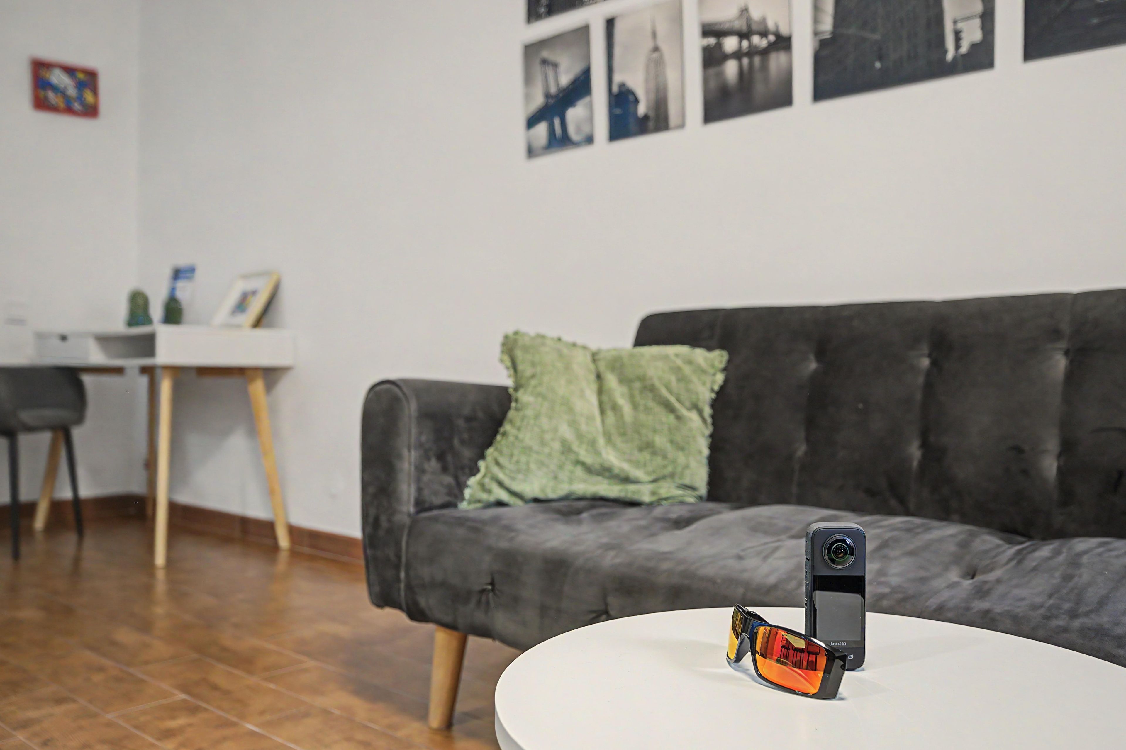 A modern living room with a grey sofa, a white table, and a smartphone on the table.