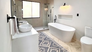 A modern bathroom with a freestanding bathtub, a large mirror, and a walk-in shower. - Villa Catalina 11 (Potrero)