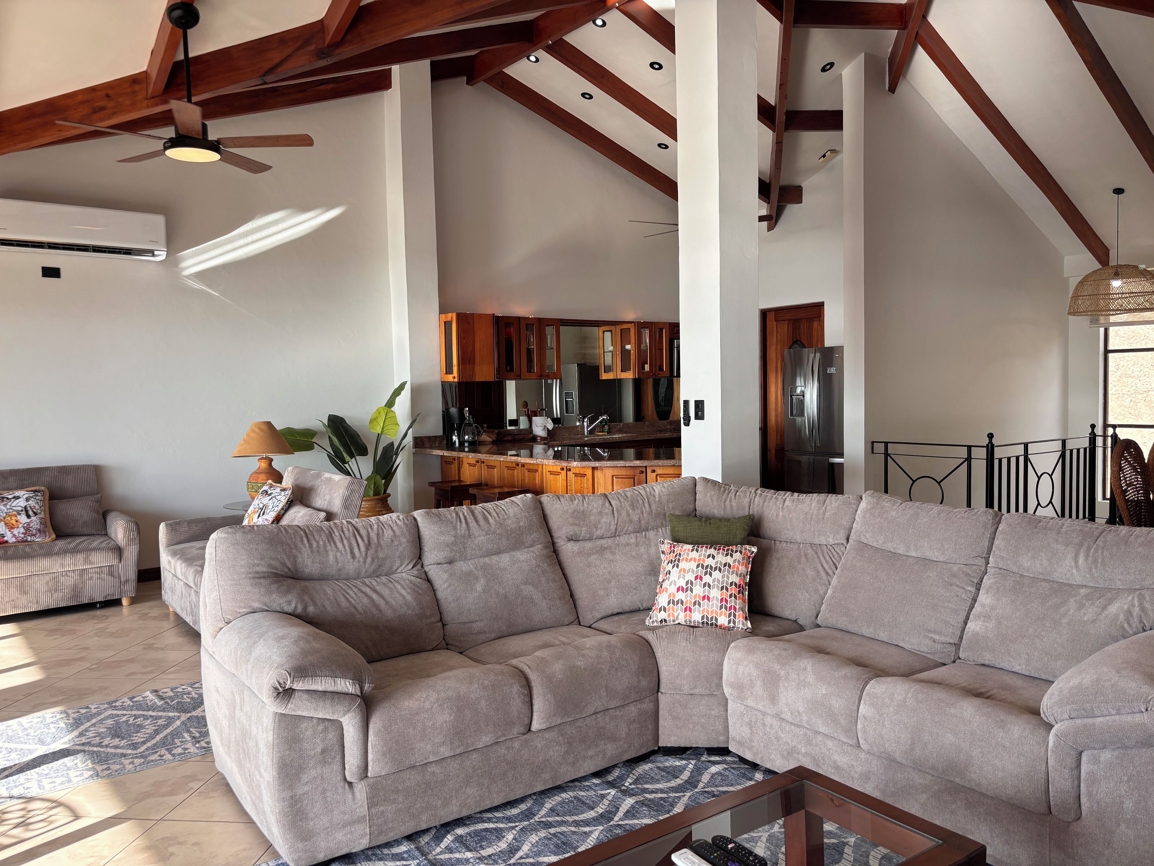 A spacious living room with a large grey sectional sofa, a coffee table, and a ceiling fan.