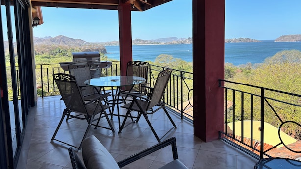A covered outdoor patio with a table and chairs, a grill, and a view of the sea and mountains. - Villa Catalina 11 (Potrero)