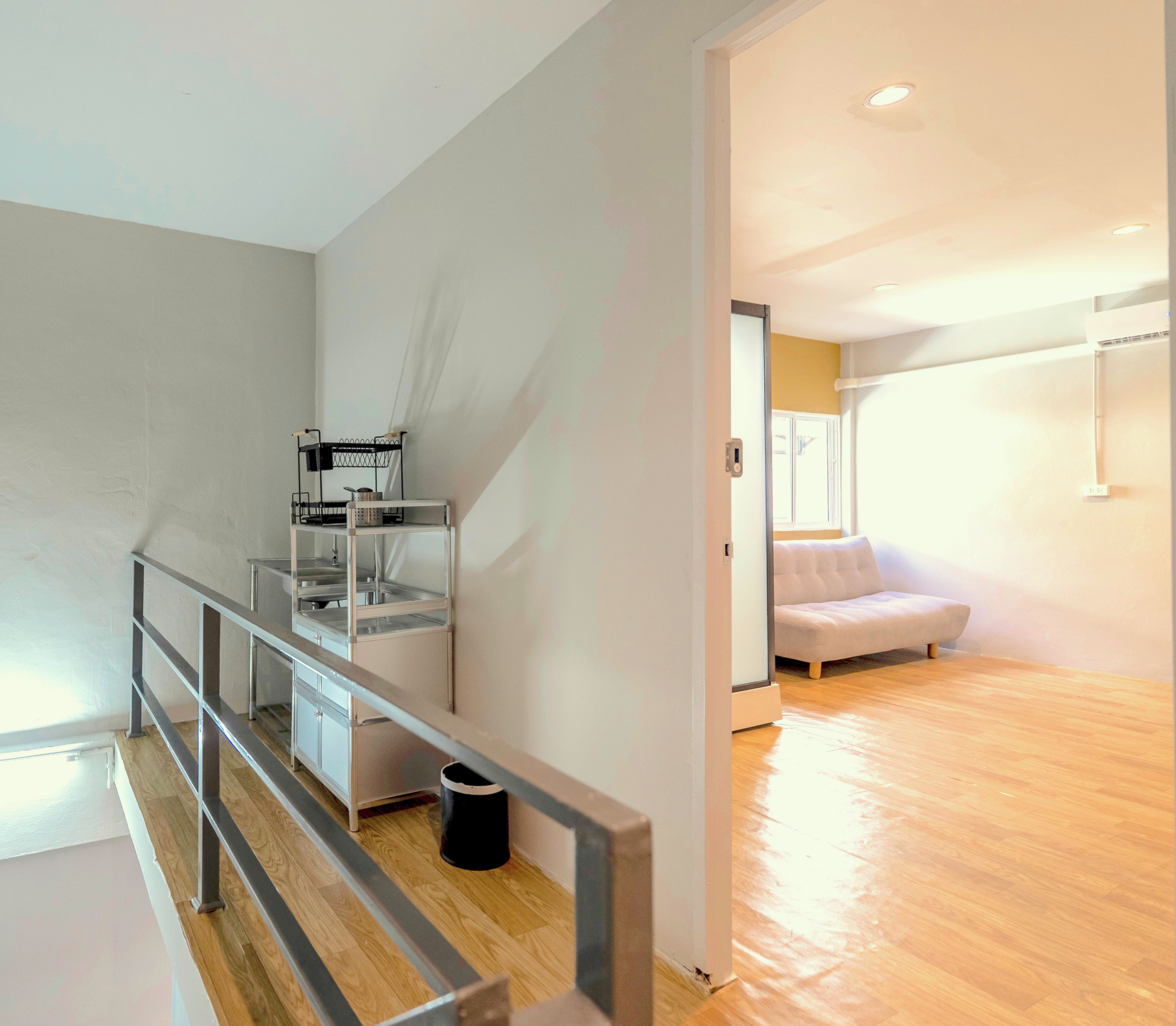 Een modern interieur met een trap, een bank en een keukenhoek.