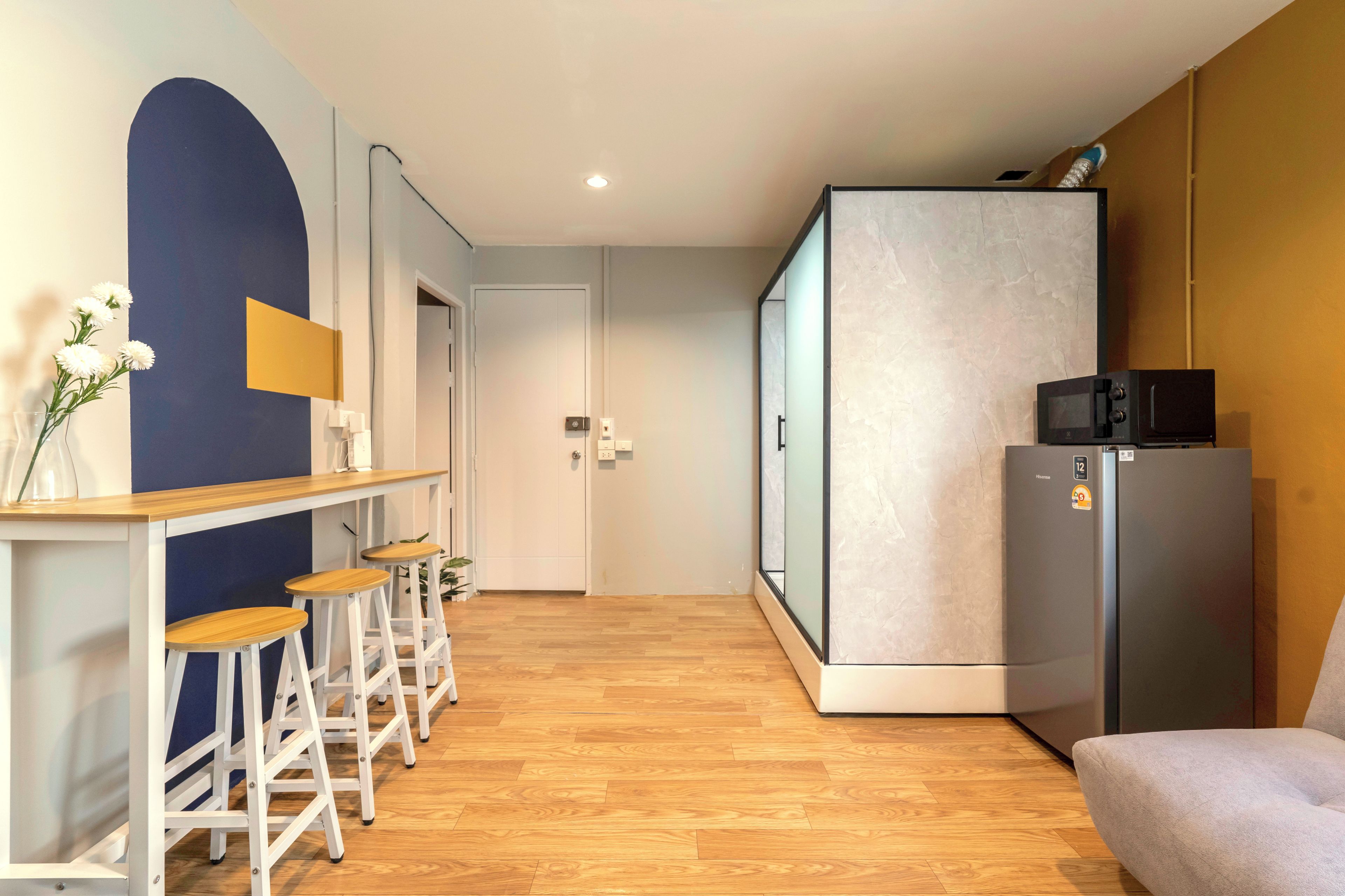 Een moderne keuken met een koelkast, magnetron en barstoelen.