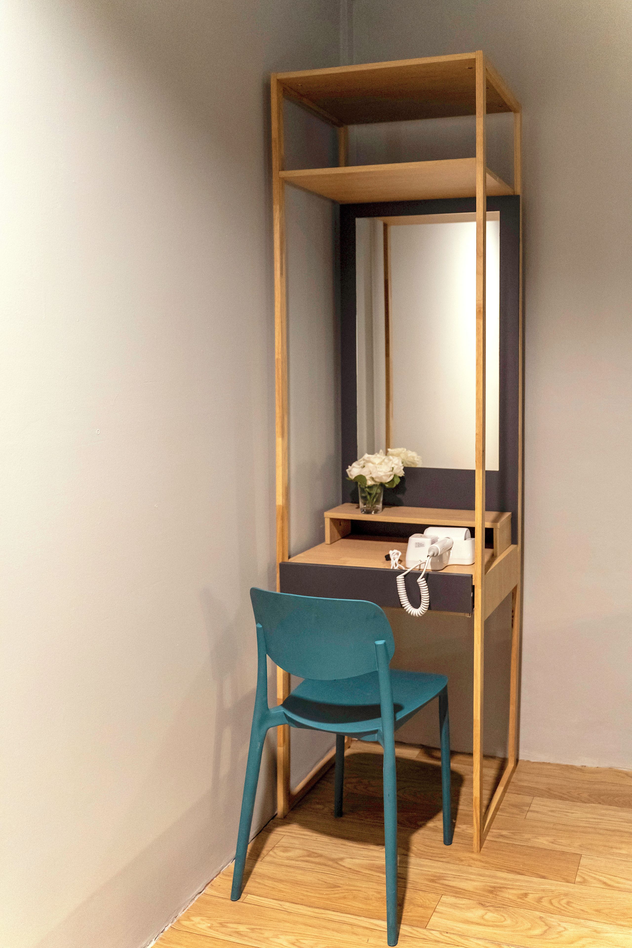 Een kleine kamer met een bureau, een stoel en een spiegel.