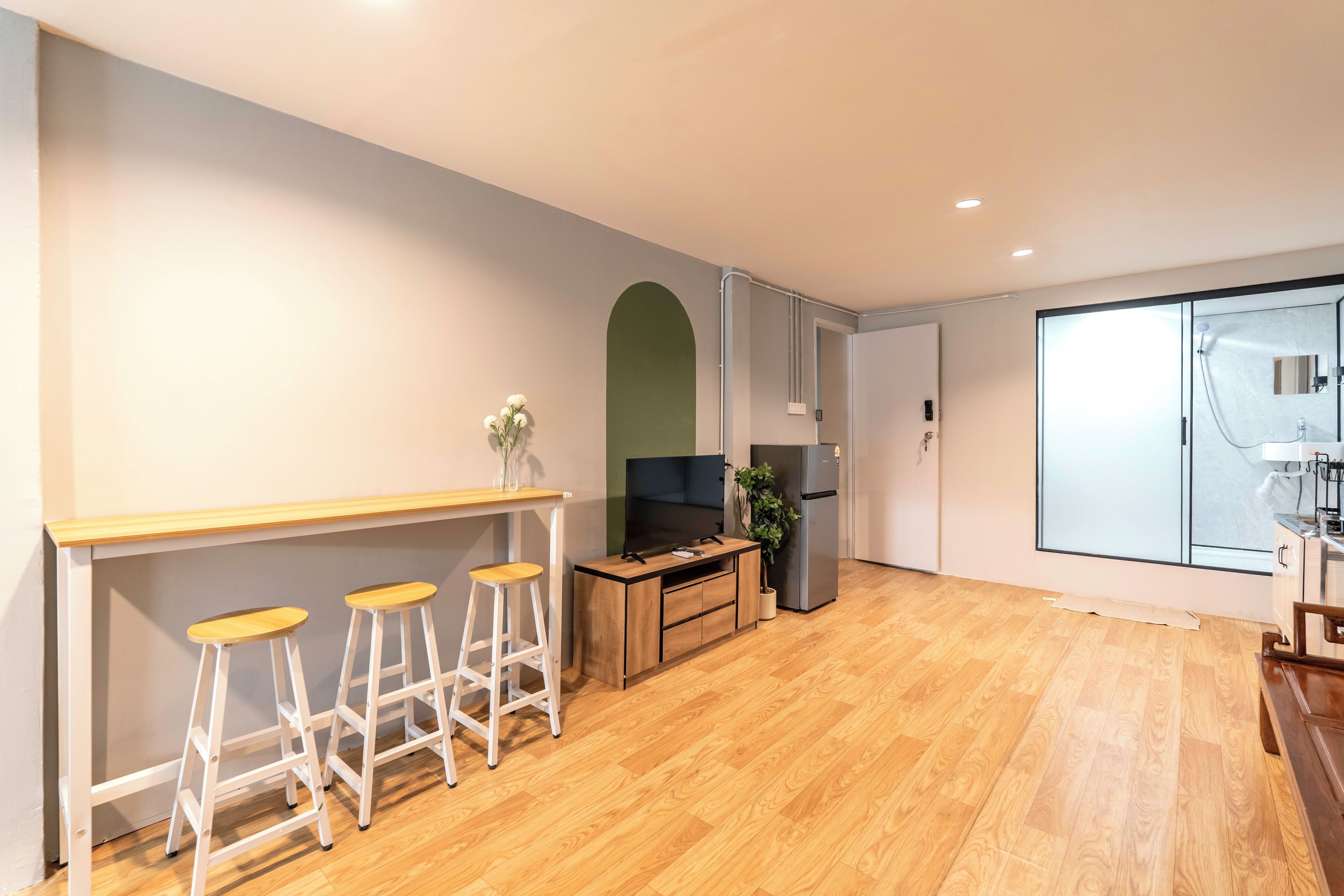Een moderne keuken met houten vloeren, een bar met krukken, een koelkast en een groot raam.
