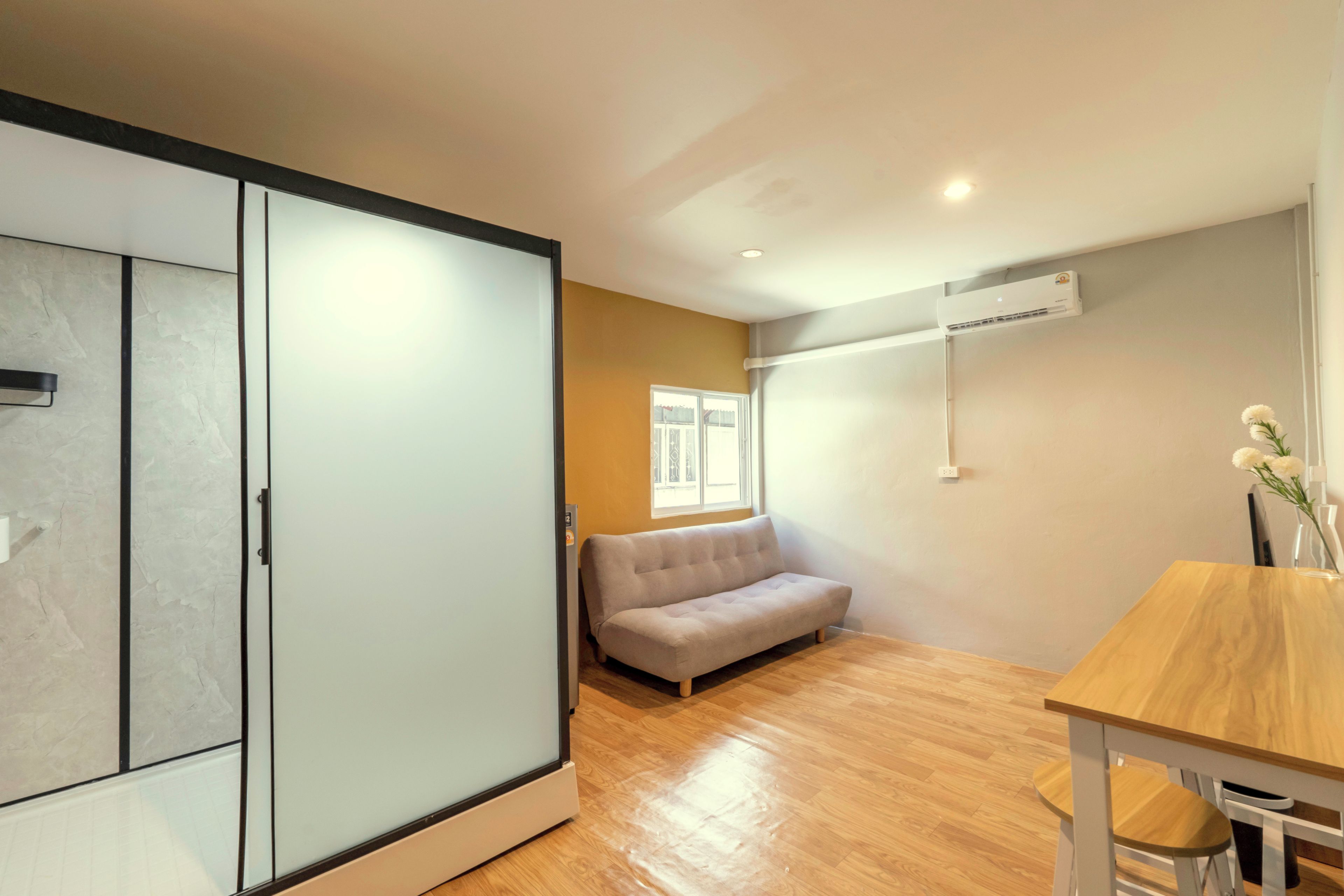 A modern room with a sofa, a dining table, and a wardrobe.