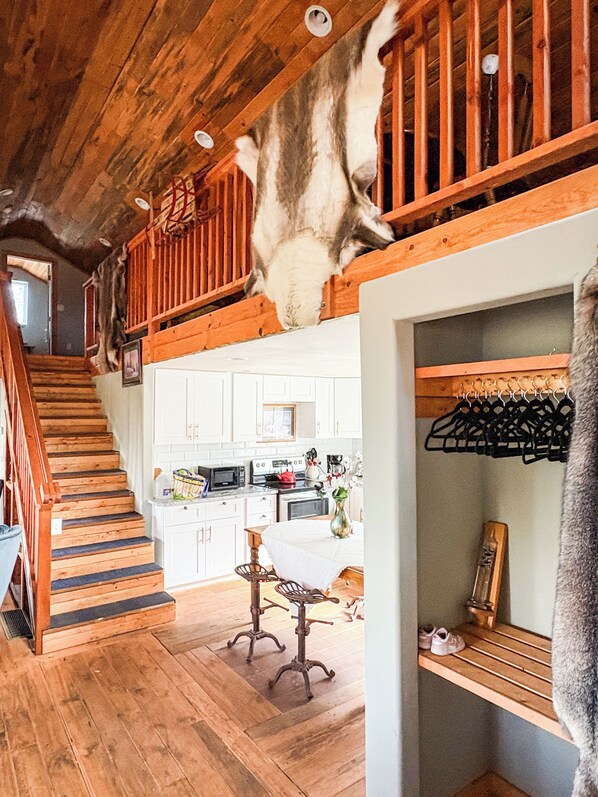 A wooden staircase leading to a loft area with a hanging animal head. - Ricks Mountain Retreat (Sedalia)