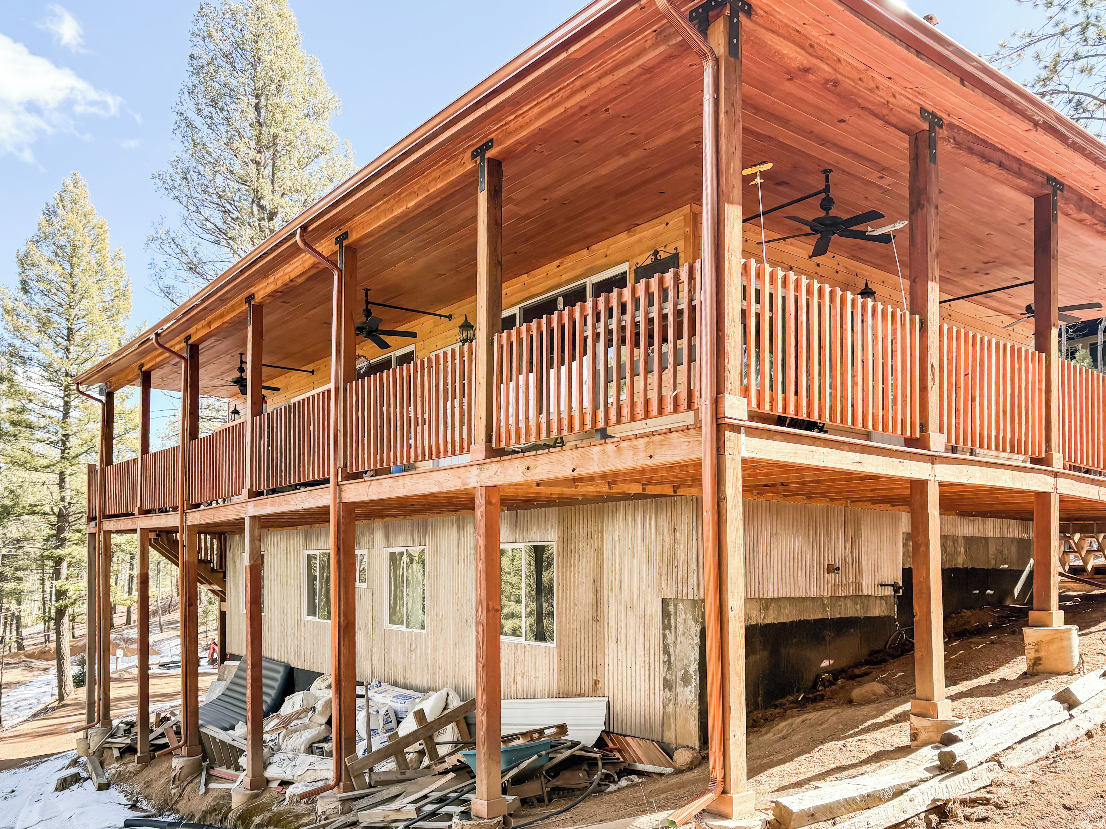 A wooden cabin with a balcony, multiple windows, and a ceiling fan.