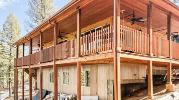A wooden cabin with a balcony, multiple windows, and a ceiling fan.