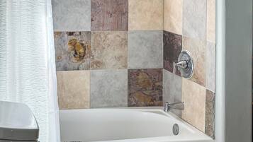 Ein Badezimmer mit Badewanne, Toilette und einem Fenster mit Toilettenartikeln.