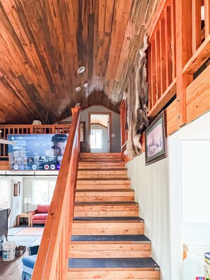 A wooden staircase with a handrail leading to a second-floor area.