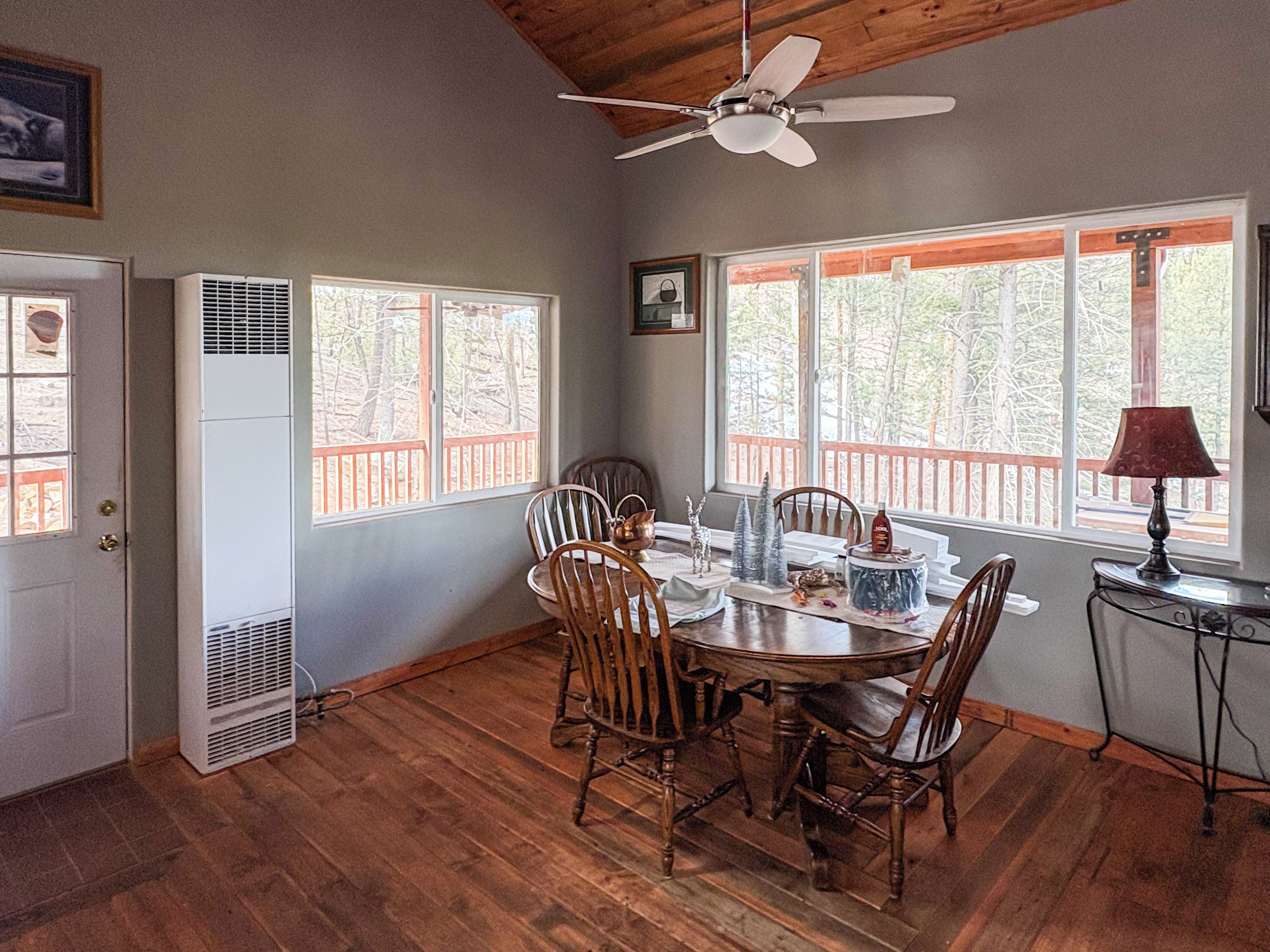 A dining area with a round table, wooden chairs, and a ceiling fan.