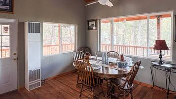 A dining area with a round table, wooden chairs, and a ceiling fan.