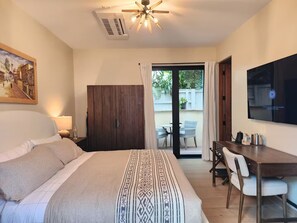 Habitación de hotel con una cama, un escritorio, un televisor y vistas al exterior.