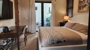Een hotelkamer met een bed, een bureau, een stoel, een lamp en een schilderij aan de muur.